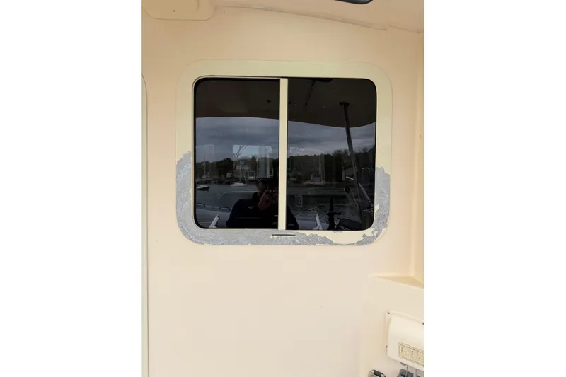  Yacht Photos Pics 2008 Island Packet SP Cruiser window with peeling paint and marina reflection.