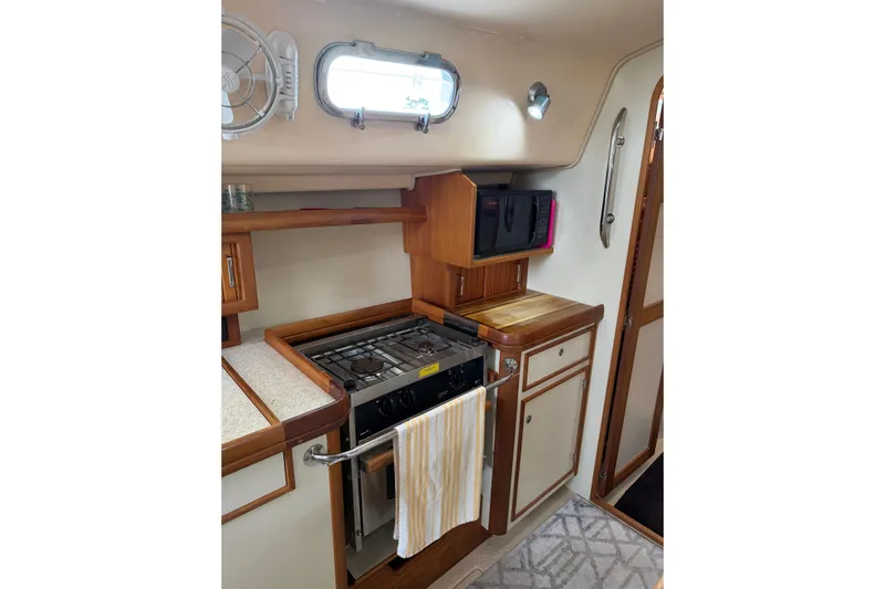  Yacht Photos Pics 2008 Island Packet SP Cruiser galley with stove, microwave, and wooden cabinetry.
