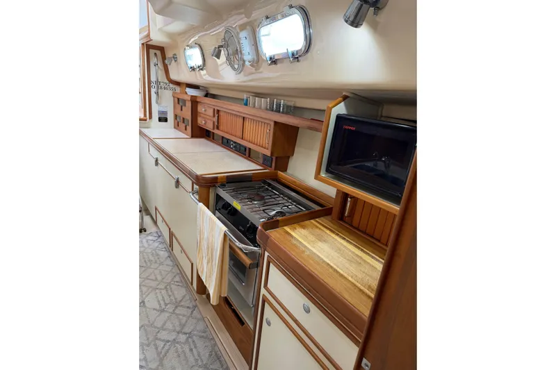  Yacht Photos Pics 2008 Island Packet SP Cruiser galley with stove, microwave, and wooden cabinetry.