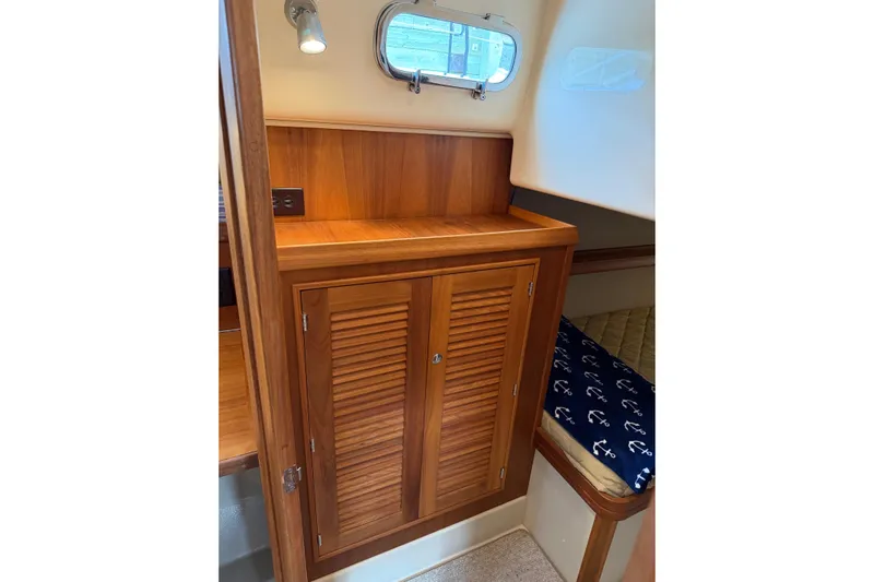  Yacht Photos Pics 2008 Island Packet SP Cruiser interior with wooden cabinet and nautical-themed bedding.