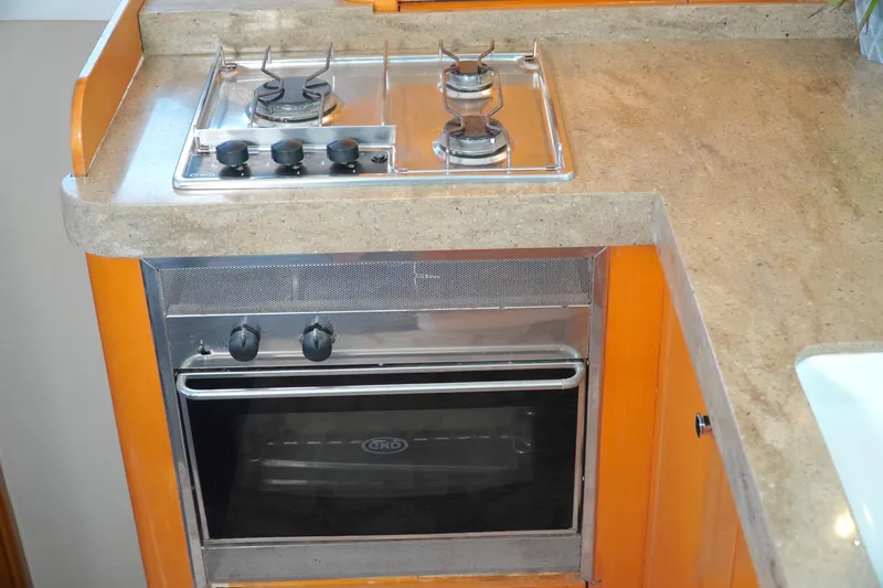 Red Yacht Photos Pics Compact kitchen in 2008 Fountaine Pajot Orana 44 with stove and oven.
