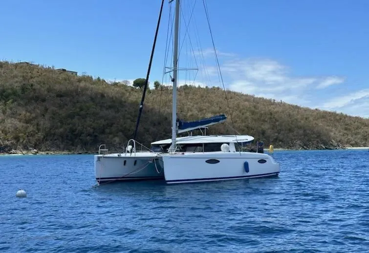 Red Yacht Photos Pics Sailing catamaran Fountaine Pajot Orana 44, 2008, anchored in clear blue waters.