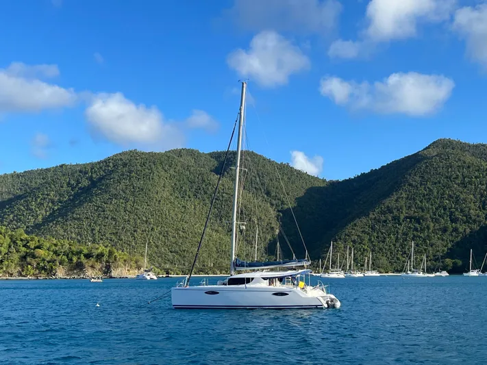 Red Yacht Photos Pics Sailing catamaran Fountaine Pajot Orana 44, 2008, anchored in scenic bay with lush hills.