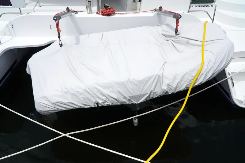 Red Yacht Photos Pics Covered dinghy on 2008 Fountaine Pajot Orana 44 catamaran, docked with ropes and hose.