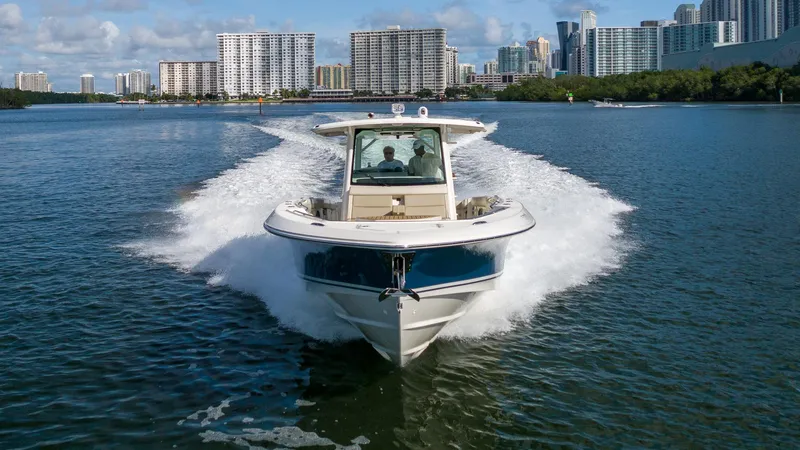  Yacht Photos Pics 2019 Boston Whaler 380 Outrage cruising on water with city skyline in background.