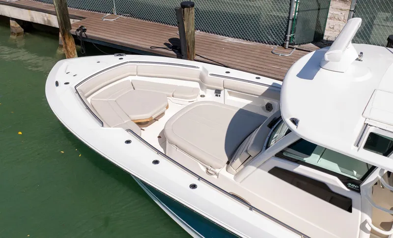  Yacht Photos Pics 2019 Boston Whaler 380 Outrage boat with spacious seating, docked by a wooden pier.
