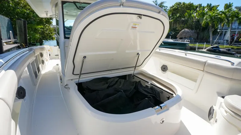 Yacht Photos Pics 2019 Boston Whaler 380 Outrage boat with open storage compartment, docked near lush greenery.
