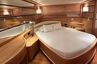 Luxurious bedroom interior of 2005 Pershing 76 yacht with modern wooden furnishings.