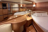 Luxurious interior of 2005 Pershing 76 yacht with elegant wood furnishings and cozy bedding.