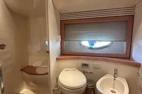 Luxurious bathroom in a 2005 Pershing 76 yacht with modern fixtures and wooden accents.