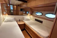 Luxurious twin cabin interior of 2005 Pershing 76 yacht with porthole windows.