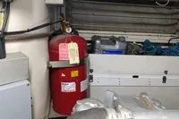 Engine room of a 2005 Pershing 76 yacht with fire extinguisher and equipment.
