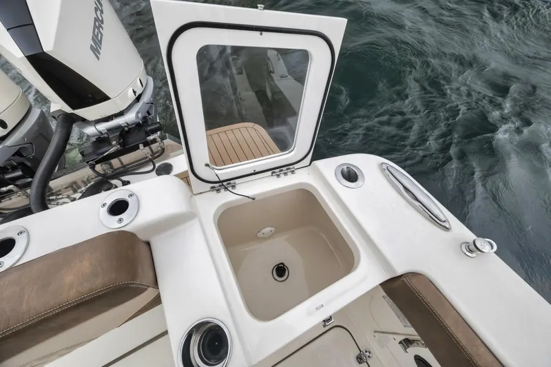 T/t Phoenix Yacht Photos Pics 2023 Scout 330 LXF boat with open storage compartment near water.