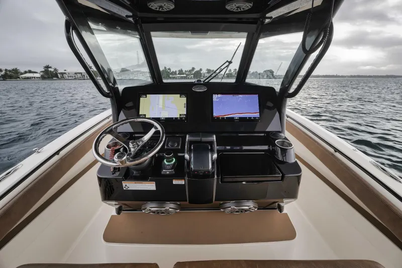T/t Phoenix Yacht Photos Pics 2023 Scout 330 LXF boat dashboard with dual screens and steering wheel on open water.