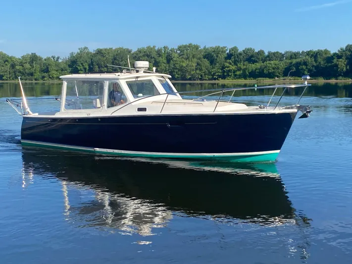 Saline Yacht Photos Pics 2005 MJM 34z Downeast boat on calm water, surrounded by lush greenery.