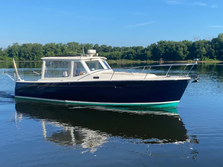 Saline Yacht Photos Pics 2005 MJM 34z Downeast boat cruising on calm water with lush green trees in the background.