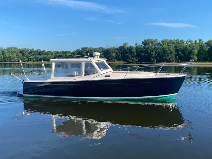 Saline Yacht Photos Pics 2005 MJM 34z Downeast boat cruising on calm water with lush green trees in the background.