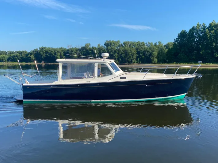 Saline Yacht Photos Pics 2005 MJM 34z Downeast boat on calm water, surrounded by lush greenery.