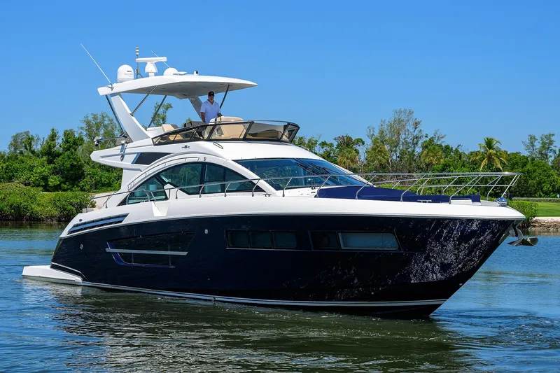 Unorthodocs Yacht Photos Pics 2018 Cruisers 60 Cantius Fly yacht cruising on a sunny day, surrounded by lush greenery.