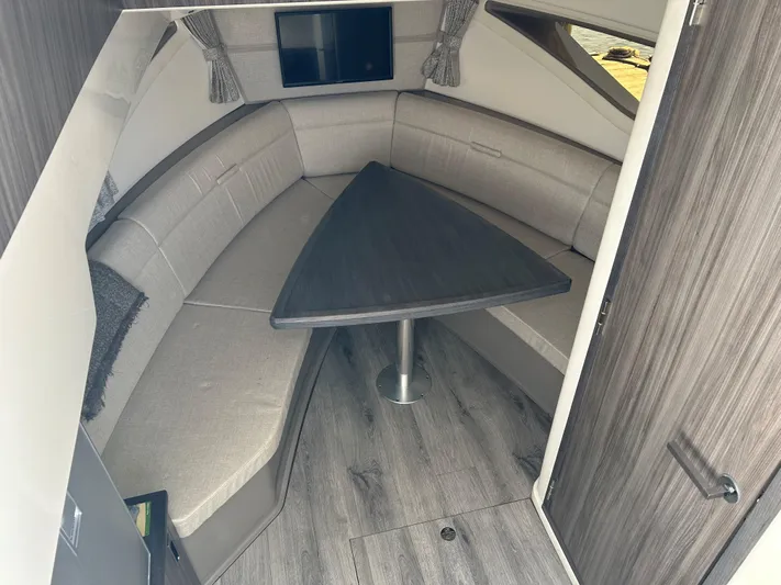  Yacht Photos Pics Interior of 2021 Sea Ray 320 DA boat with cushioned seating and triangular table.