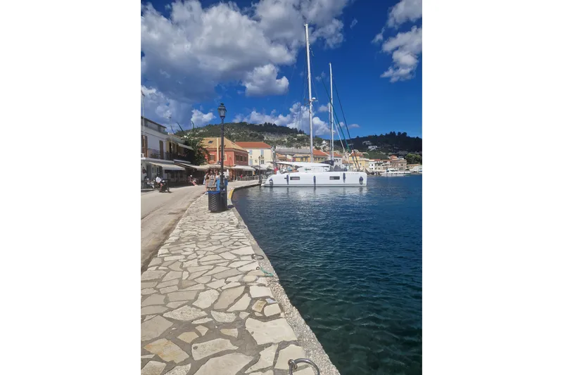 Eadan Doire Yacht Photos Pics Seaside promenade with a 2017 Lagoon 42 catamaran docked, under a vibrant blue sky.