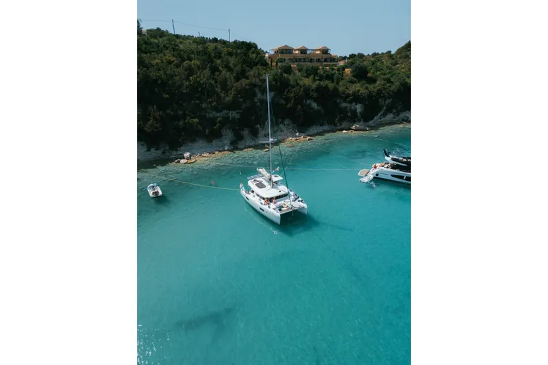 Eadan Doire Yacht Photos Pics Lagoon 42 catamaran, 2017 model, anchored in clear turquoise waters near a lush coastline.