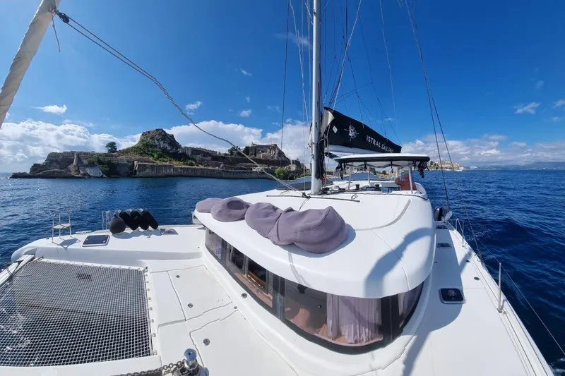 Eadan Doire Yacht Photos Pics 2017 Lagoon 42 catamaran sailing near a scenic coastal fortress under a clear blue sky.