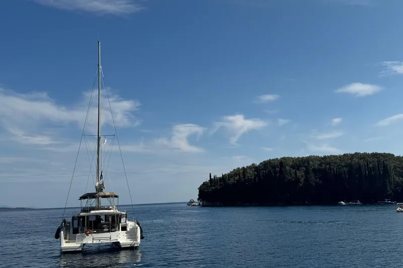 Eadan Doire Yacht Photos Pics Sailing catamaran Lagoon 42, 2017 model, anchored near a lush island under a clear sky.
