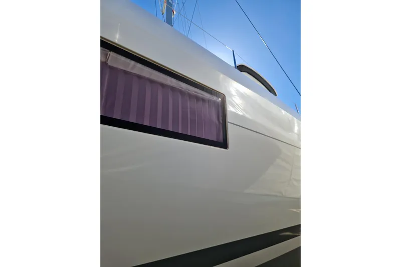 Eadan Doire Yacht Photos Pics Side view of a 2017 Lagoon 42 catamaran with window detail against blue sky.