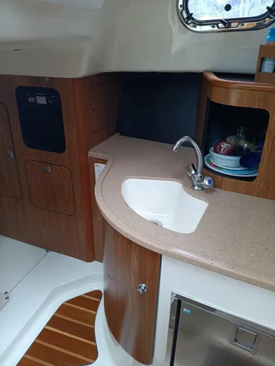Gracie Yacht Photos Pics 2009 Pursuit 310 OS boat interior with kitchenette, sink, and wooden cabinetry.