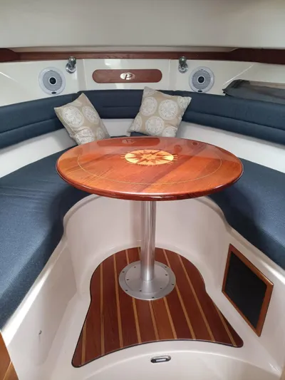 Gracie Yacht Photos Pics 2009 Pursuit 310 OS cabin with wooden table and cushioned seating.