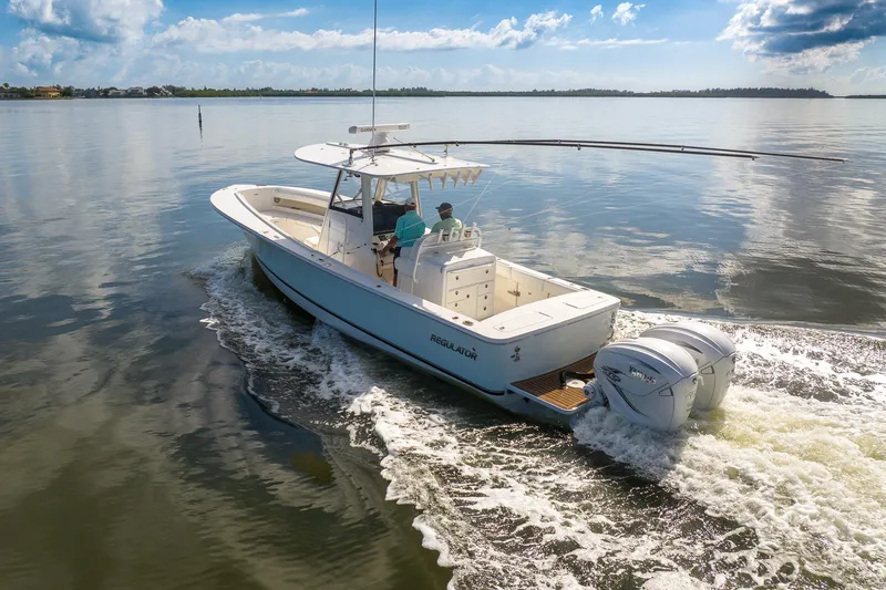  Yacht Photos Pics 2021 Regulator 31 boat cruising on calm water under a partly cloudy sky.