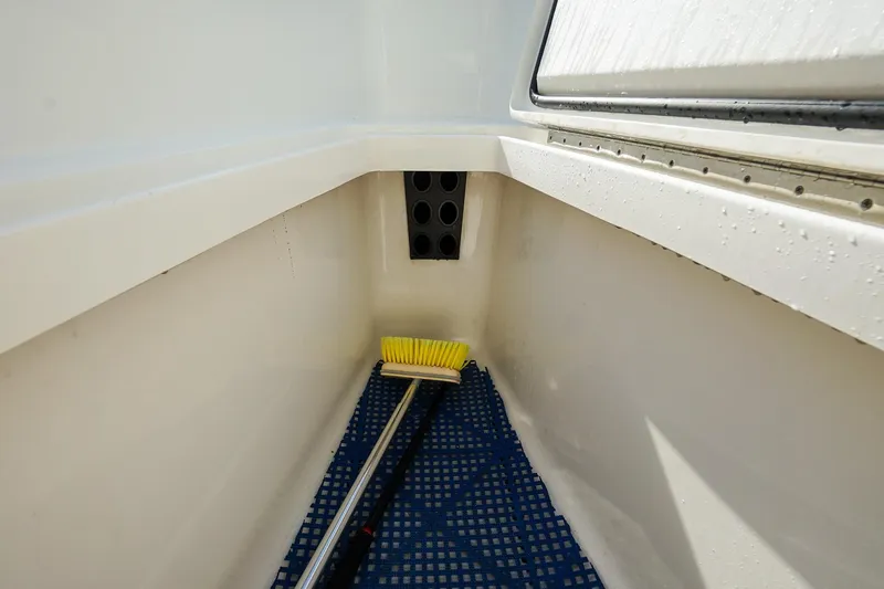  Yacht Photos Pics 2021 Regulator 31 boat storage compartment with cleaning brush and blue mat.