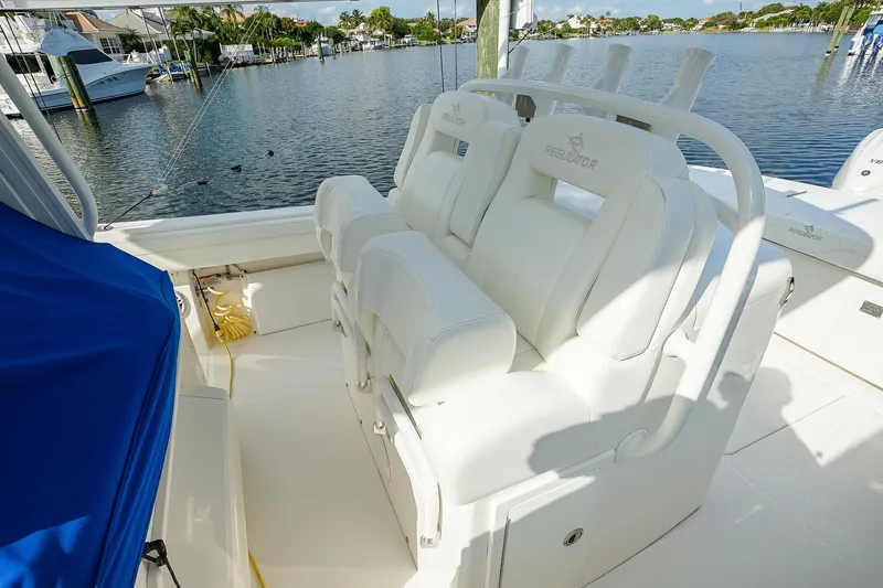  Yacht Photos Pics 2021 Regulator 31 boat with white seating, docked by a serene waterfront.