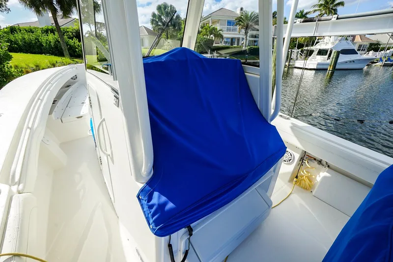  Yacht Photos Pics 2021 Regulator 31 boat interior with blue seat cover, docked by waterfront homes.