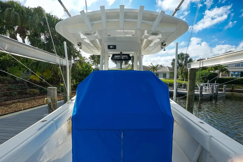 Yacht Photos Pics 2021 Regulator 31 boat with blue cover, docked near lush greenery and waterway.