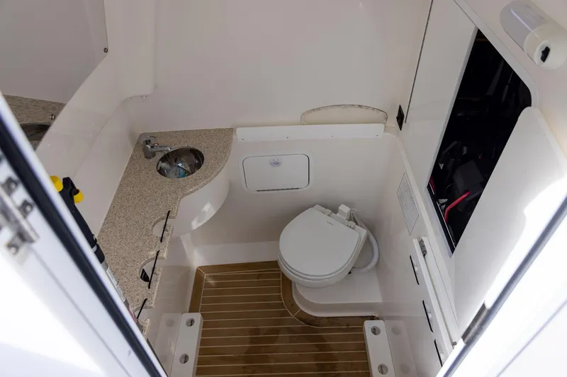  Yacht Photos Pics 2021 Regulator 31 boat interior with compact bathroom, featuring a toilet and sink.