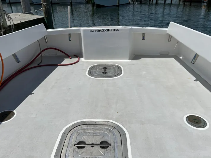 Lady Grace Yacht Photos Pics Open deck of 2022 Wesmac 38 boat at dock, featuring storage hatches and "Lady Grace Charters" signage.