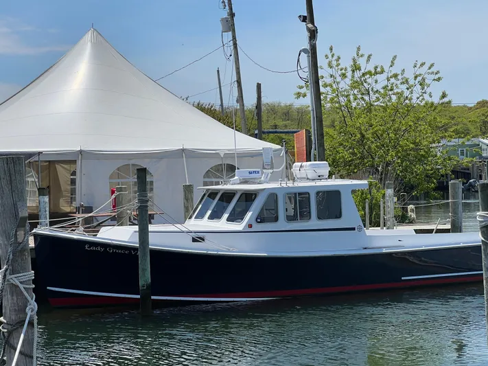 Lady Grace Yacht Photos Pics 2022 Wesmac 38 boat docked near a white tent and trees.