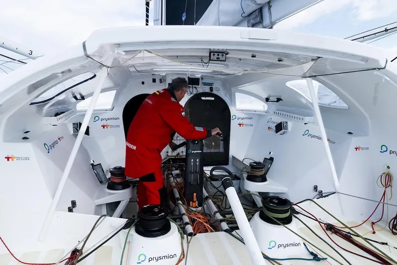 Prysmian Yacht Photos Pics Person in red suit inside 2015 Multiplast Imoca 60 yacht cockpit.
