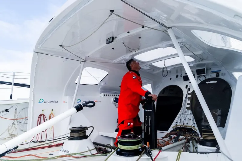Prysmian Yacht Photos Pics Person in red gear on a 2015 Multiplast Imoca 60 sailboat deck.