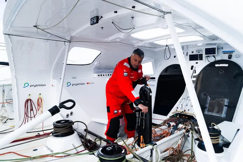 Prysmian Yacht Photos Pics Sailor in red gear operating controls on a 2015 Multiplast Imoca 60 yacht.