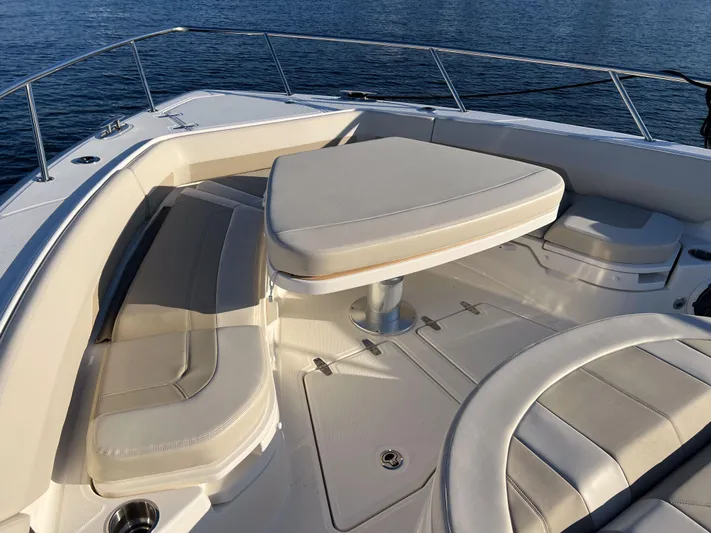  Yacht Photos Pics 2023 Boston Whaler 420 Outrage boat interior with cushioned seating and table.