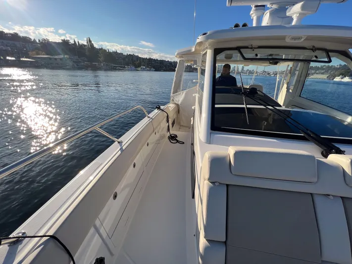  Yacht Photos Pics 2023 Boston Whaler 420 Outrage cruising on a sunny day, reflecting water and scenic shoreline.