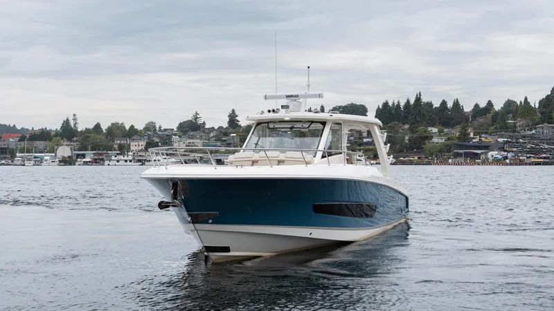  Yacht Photos Pics 2023 Boston Whaler 420 Outrage boat on water, with scenic shoreline background.