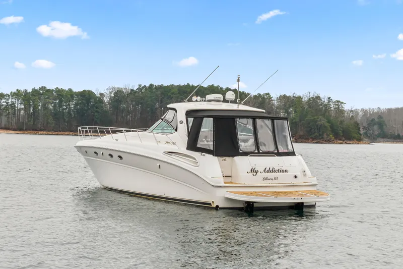 My Addiction Yacht Photos Pics 2001 Sea Ray Sundancer 510 yacht on calm water, surrounded by trees under a clear sky.