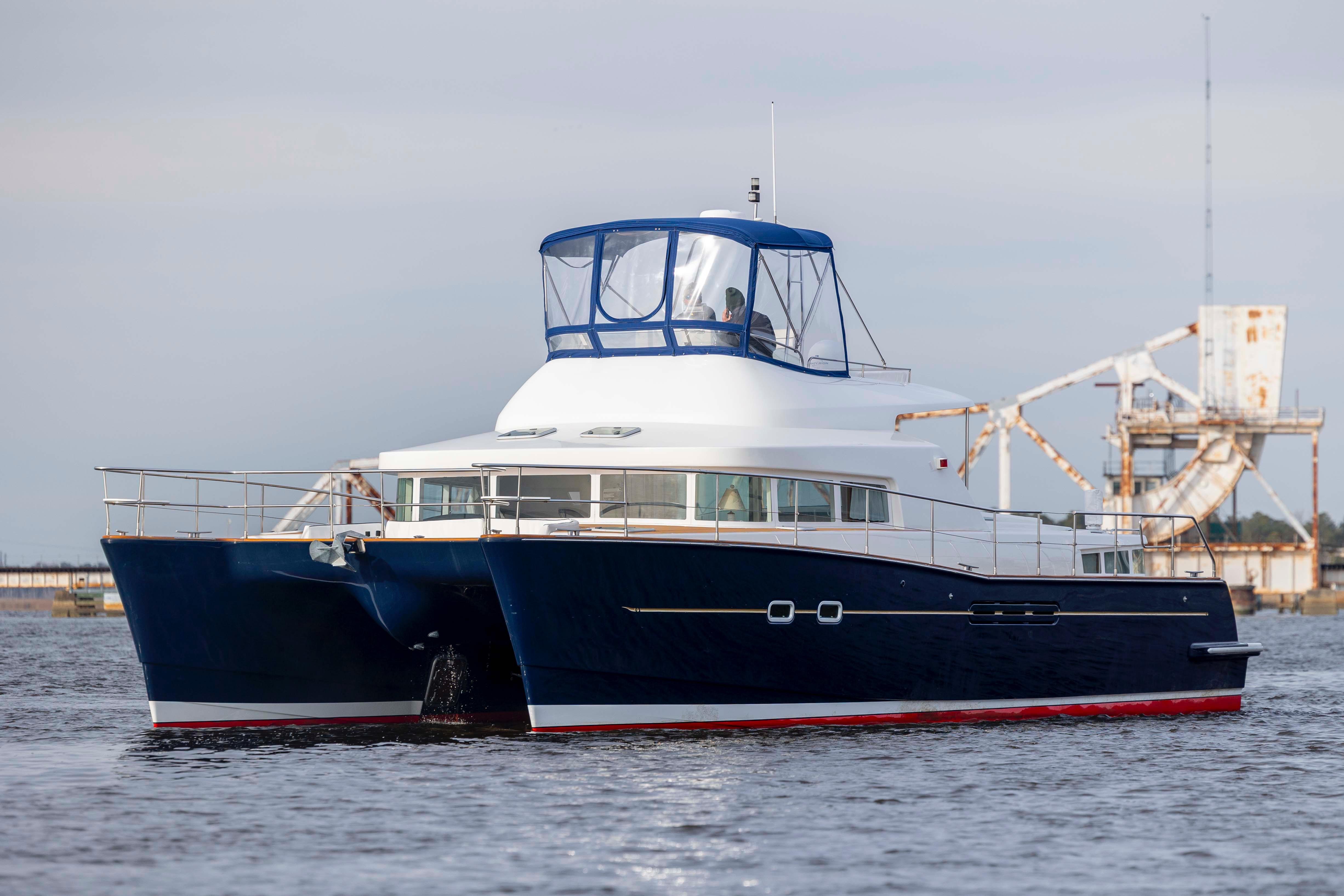 2004 Lagoon 43 PC catamaran cruising on water, featuring a sleek blue and white design.