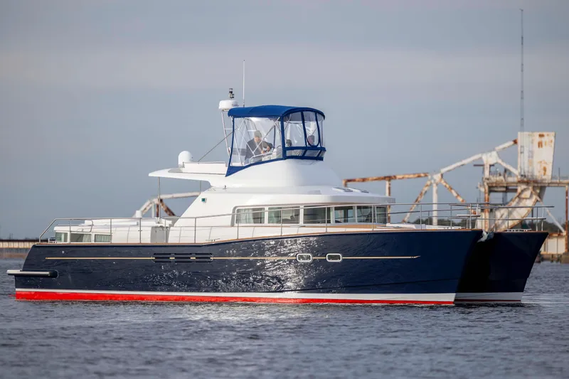  Yacht Photos Pics 2004 Lagoon 43 PC yacht with blue hull and red trim on calm water.