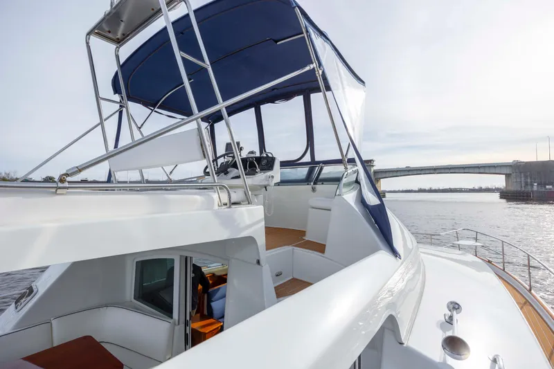  Yacht Photos Pics 2004 Lagoon 43 PC yacht with blue canopy, docked near a bridge on a sunny day.