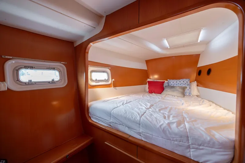  Yacht Photos Pics Cozy cabin interior of 2004 Lagoon 43 PC yacht with comfortable bedding and porthole windows.